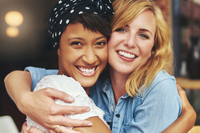 two female friends smiling and giving each other a hug