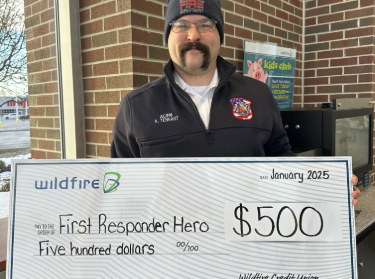 Andrew Tennant smiling and holding a check for 500 dollars