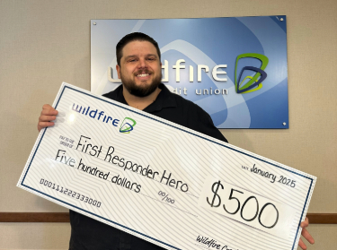 Joshua Stanard smiling and holding a check for 500 dollars