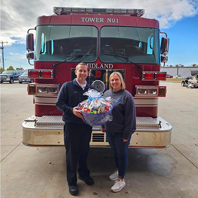 Rachel delivering basket of goods to Midland Fire Department for CU Kind Day 2024